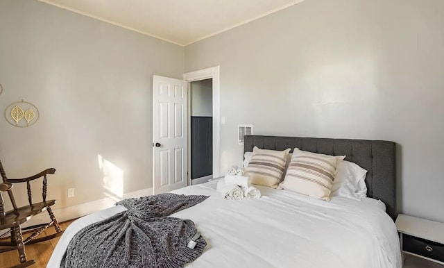 bedroom featuring ornamental molding, wood finished floors, and baseboards