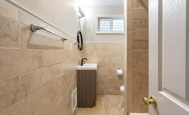 bathroom featuring toilet, tile patterned flooring, tile walls, and vanity