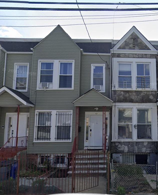 townhome / multi-family property with a fenced front yard and stone siding