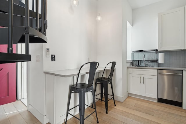 kitchen with light countertops, white cabinets, a sink, and light wood finished floors