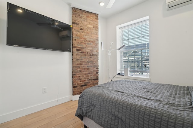 bedroom featuring light wood finished floors, baseboards, and a wall mounted AC