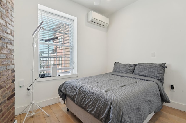 bedroom featuring an AC wall unit, wood finished floors, and baseboards