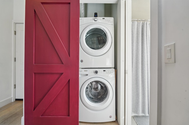 laundry room featuring laundry area, stacked washer / dryer, and wood finished floors