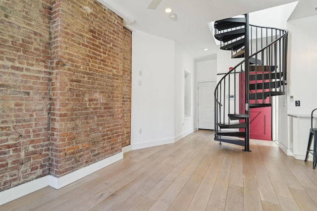 interior space with light wood finished floors, baseboards, brick wall, stairs, and recessed lighting