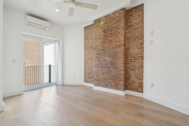 unfurnished room featuring brick wall, light wood finished floors, a wall mounted air conditioner, and baseboards