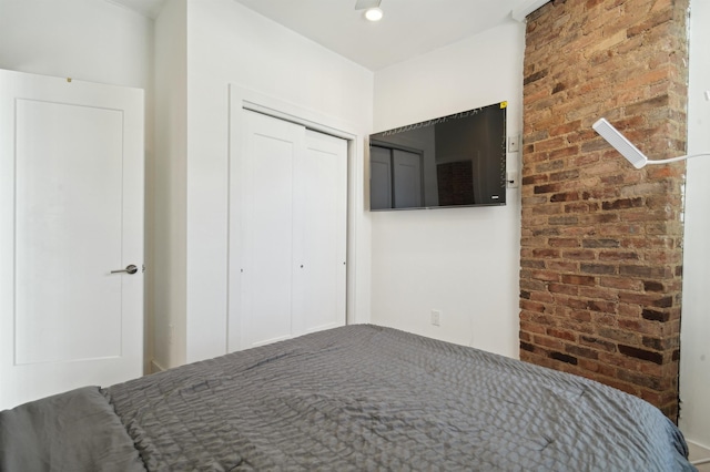 unfurnished bedroom featuring a closet and brick wall