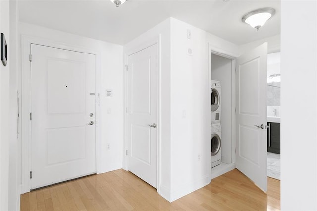washroom with laundry area, light wood-style flooring, and stacked washer / dryer