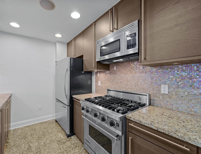 10 Regent St Unit 209X, Jersey City, NJ 07302 - kitchen with stainless steel appliances, decorative backsplash, baseboards, dark brown cabinetry, and light stone countertops
