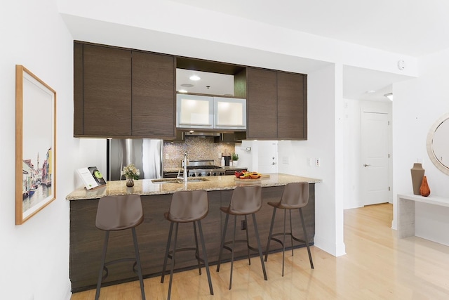10 Regent St Unit 209X, Jersey City, NJ 07302 - kitchen featuring dark brown cabinets, a kitchen breakfast bar, light wood-type flooring, and a sink