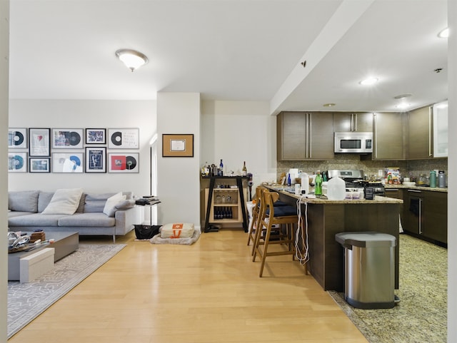 10 Regent St # 308, Jersey City, NJ 07302 - kitchen featuring stainless steel microwave, gas range, decorative backsplash, a peninsula, and a breakfast bar area