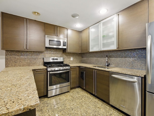 10 Regent St # 308, Jersey City, NJ 07302 - kitchen with appliances with stainless steel finishes, backsplash, dark brown cabinetry, and glass insert cabinets