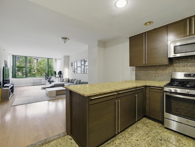 10 Regent St # 308, Jersey City, NJ 07302 - kitchen with appliances with stainless steel finishes, dark brown cabinetry, open floor plan, a peninsula, and recessed lighting