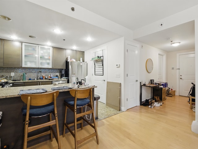 10 Regent St # 308, Jersey City, NJ 07302 - kitchen with freestanding refrigerator, light wood-style floors, decorative backsplash, glass insert cabinets, and light stone countertops