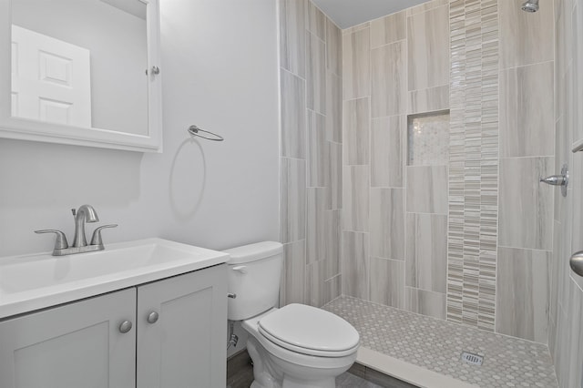 bathroom featuring tiled shower, toilet, and vanity