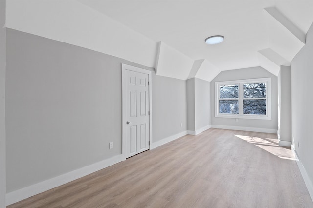 additional living space with light hardwood / wood-style floors and lofted ceiling