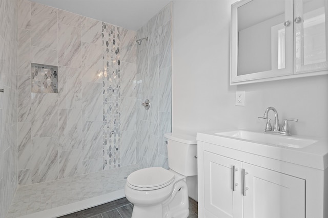 bathroom with tiled shower, toilet, and vanity