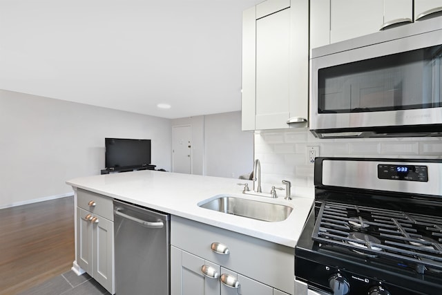 1 Congress St Unit 304, Jersey City, NJ 07307 - kitchen featuring appliances with stainless steel finishes, light countertops, a peninsula, decorative backsplash, and dark wood-type flooring