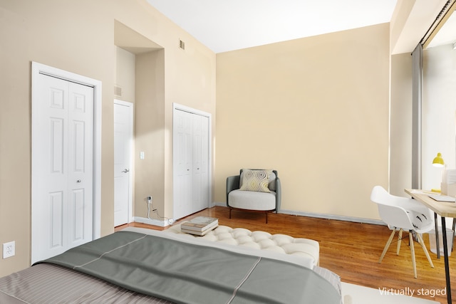 bedroom with multiple closets, visible vents, and wood finished floors