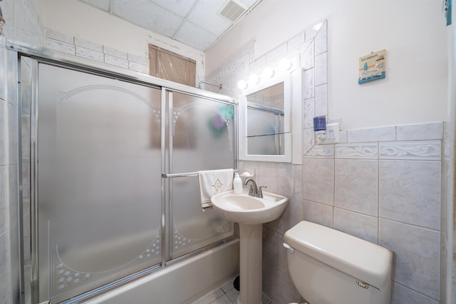 bathroom featuring visible vents, toilet, tile walls, a drop ceiling, and a sink