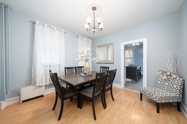 dining space featuring baseboards, light wood finished floors, and a notable chandelier