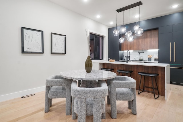 dining space with sink and light hardwood / wood-style flooring