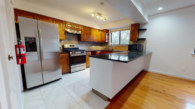 602 Sanderling Ct Unit 602, Secaucus, NJ 07094 - kitchen with a peninsula, brown cabinets, stainless steel appliances, under cabinet range hood, and tasteful backsplash