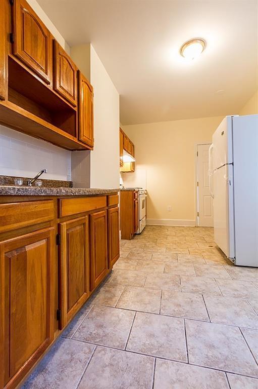 69 Belmont Ave, Jersey City, NJ 07304 - kitchen featuring white appliances, open shelves, baseboards, and brown cabinets