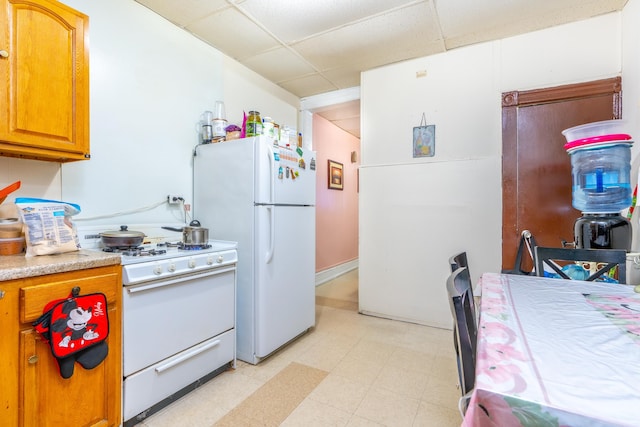 kitchen with a paneled ceiling and white appliances