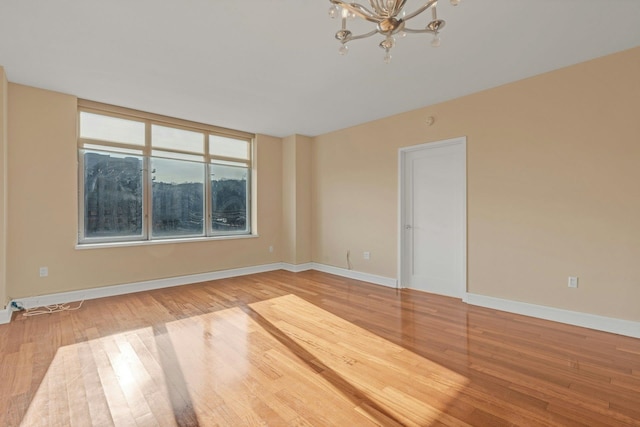 empty room with hardwood / wood-style flooring and a chandelier