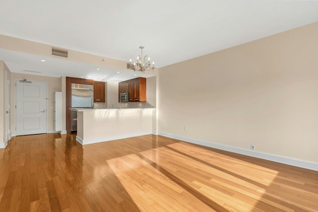 unfurnished living room featuring an inviting chandelier and light wood-type flooring