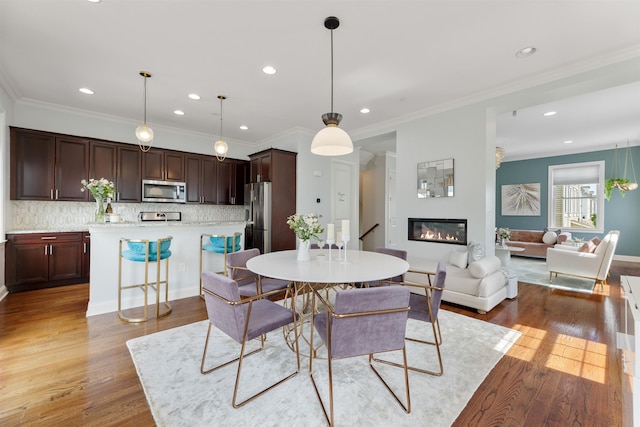 129 Roosevelt Dr, Wood-Ridge, NJ 07075 - dining room with light wood-style flooring, recessed lighting, a glass covered fireplace, and ornamental molding