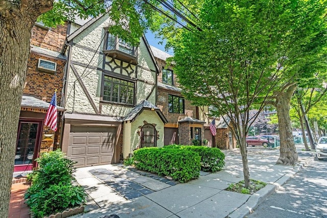 110 56th St, West New York, NJ 07093 - tudor-style house featuring a garage, driveway, and brick siding
