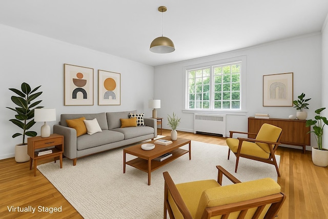 110 56th St, West New York, NJ 07093 - living room featuring radiator, light wood-style flooring, ornamental molding, and baseboards