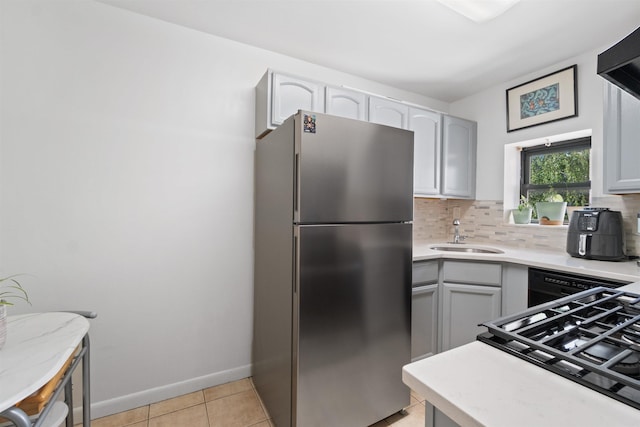 kitchen with light tile patterned floors, stainless steel fridge, gray cabinetry, tasteful backsplash, and sink