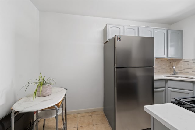 kitchen with gray cabinetry, stainless steel fridge, tasteful backsplash, and sink