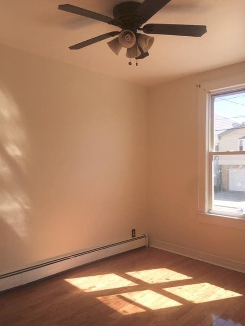 empty room featuring a baseboard heating unit and hardwood / wood-style floors