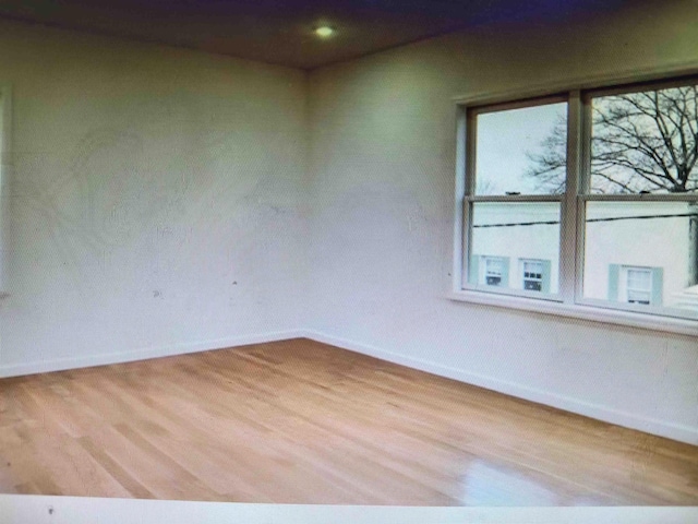 spare room featuring baseboards and wood finished floors