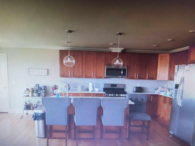 kitchen featuring stainless steel microwave, range, refrigerator, and hanging light fixtures