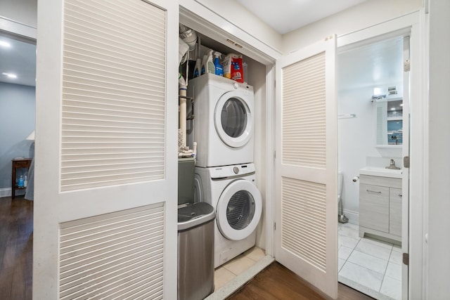 laundry room featuring stacked washer and dryer and dark tile patterned flooring