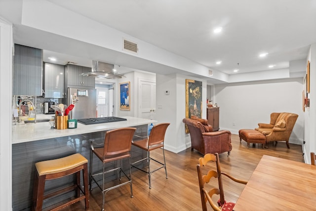 kitchen featuring stainless steel appliances, a breakfast bar, light wood-type flooring, and gray cabinets