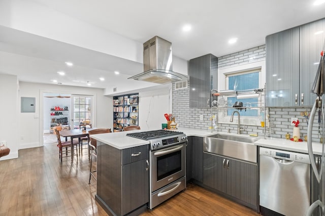 kitchen with sink, kitchen peninsula, electric panel, island exhaust hood, and stainless steel appliances