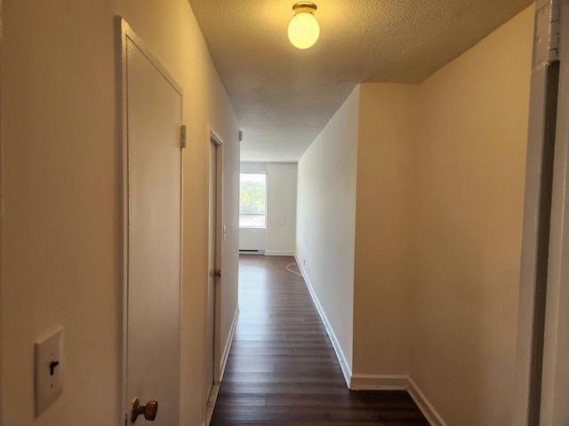 hall featuring baseboards, a textured ceiling, and dark wood finished floors