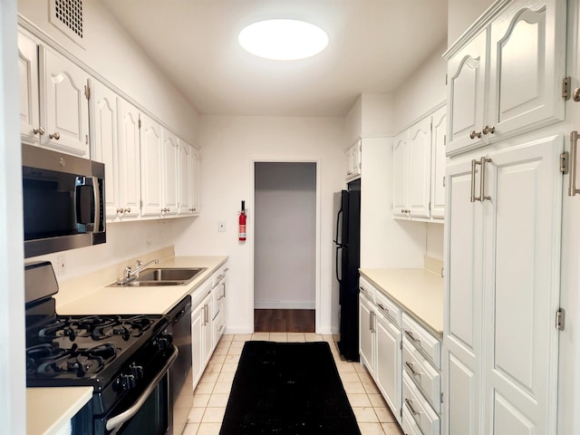 kitchen with a sink, black appliances, light tile patterned floors, white cabinetry, and visible vents