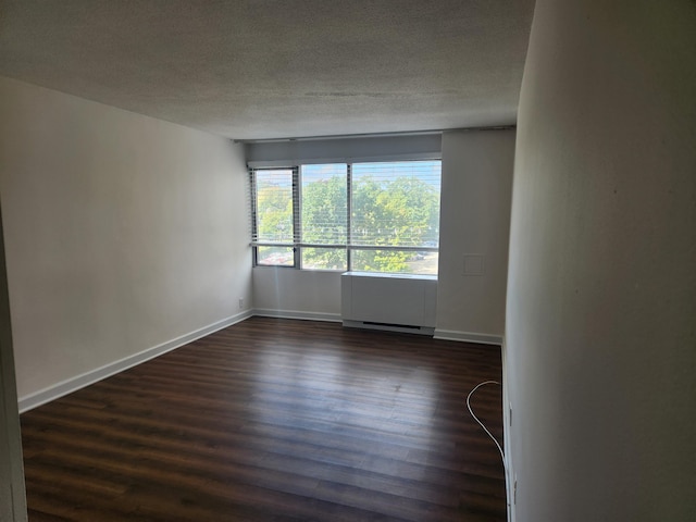 unfurnished room featuring baseboards, dark wood-style flooring, and a textured ceiling