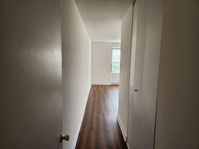 corridor featuring baseboards and dark wood-style floors