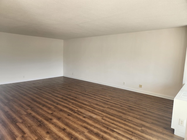 unfurnished room with dark wood-type flooring and baseboards