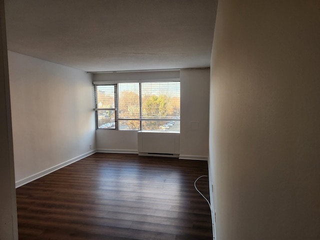 empty room with dark wood finished floors and baseboards