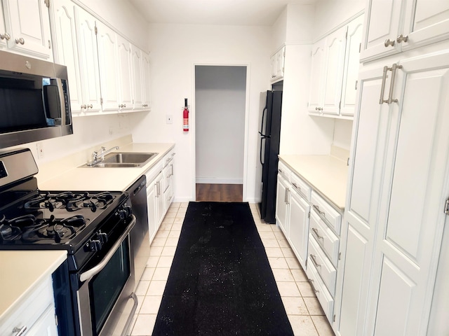 kitchen featuring white cabinets, stainless steel appliances, light countertops, and a sink