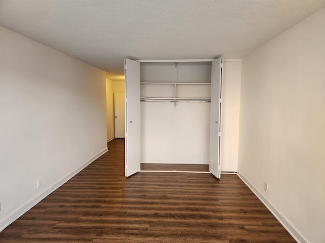 unfurnished bedroom featuring baseboards, dark wood-style floors, and a closet