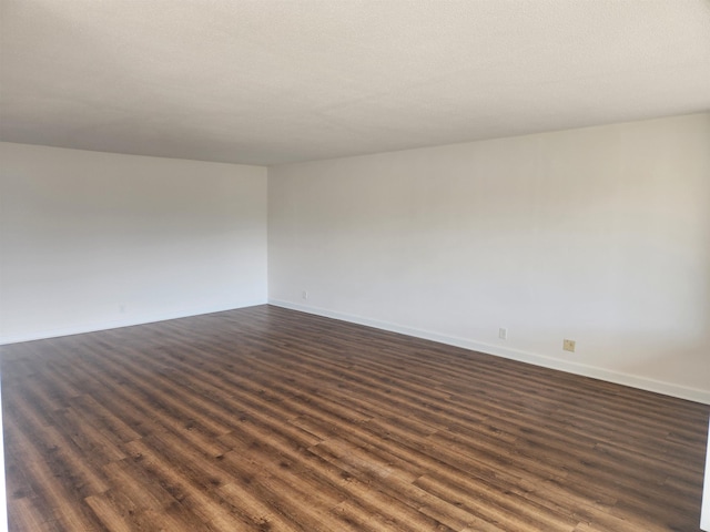 unfurnished room with baseboards and dark wood finished floors